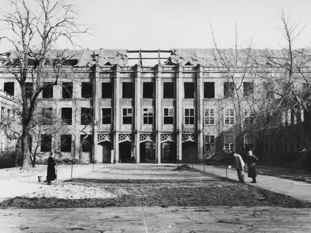 schwarz-weiß Fotografie des zerstörten Gebäudes vom Innenhof, fehlendes Dach und zerstörte Fenster erkennbar, 