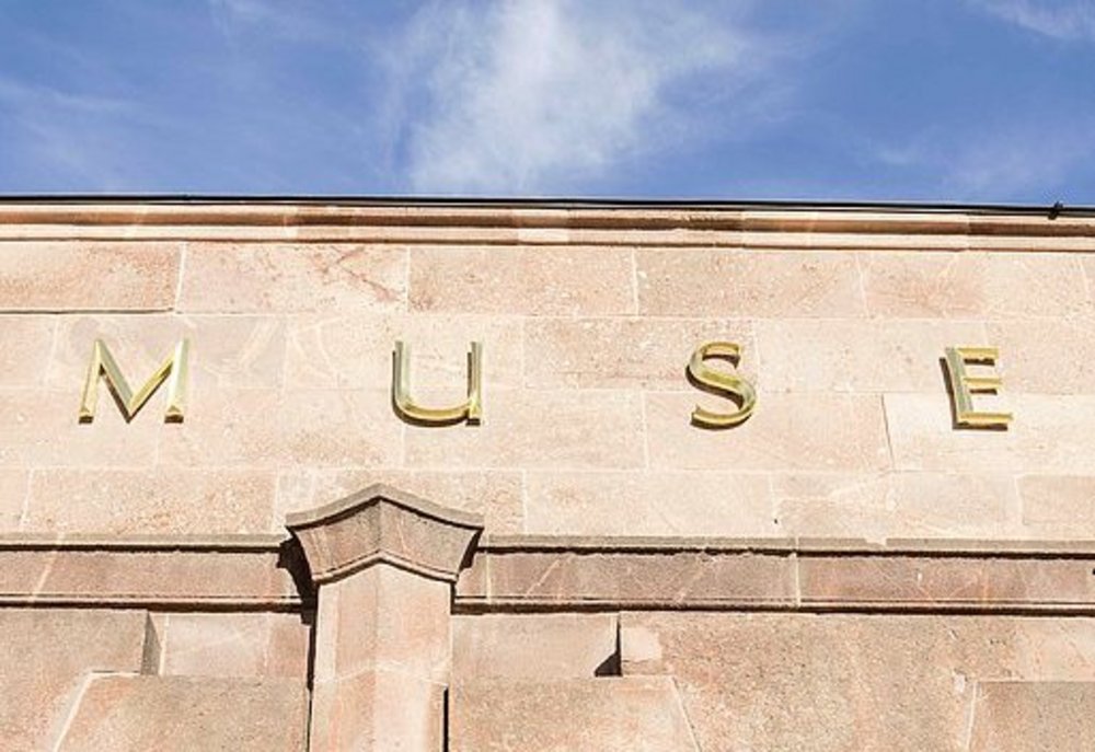 Detailaufnahme der goldenen Buchstaben, die den Museumsnamen am Gebäude bilden