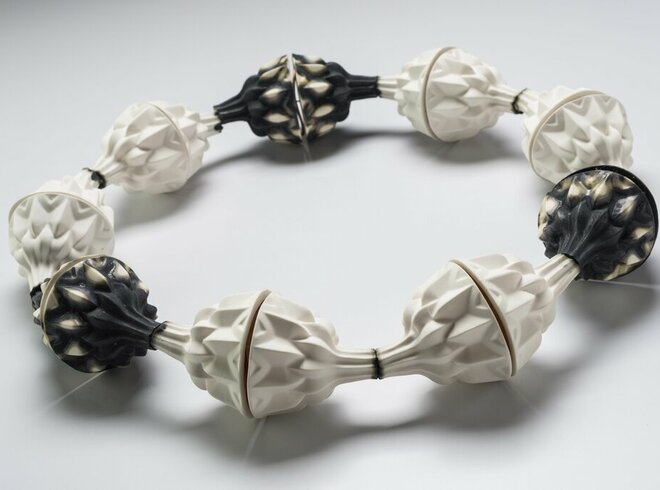 Ein modisches Halsband aus großen, geometrisch geformten Perlen in Weiß und Schwarz, abwechselnd angeordnet auf einer flexiblen Schnur