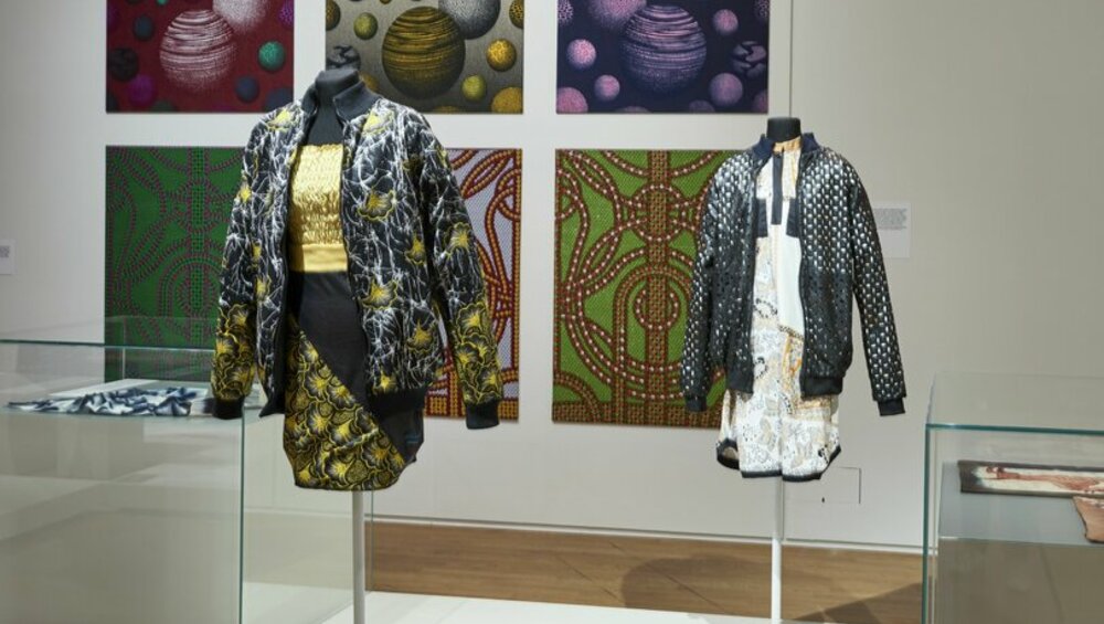 Innenansicht einer Kunstgalerie mit einer Vielfalt an ausgestellten Bildern und Kleidungsstilen