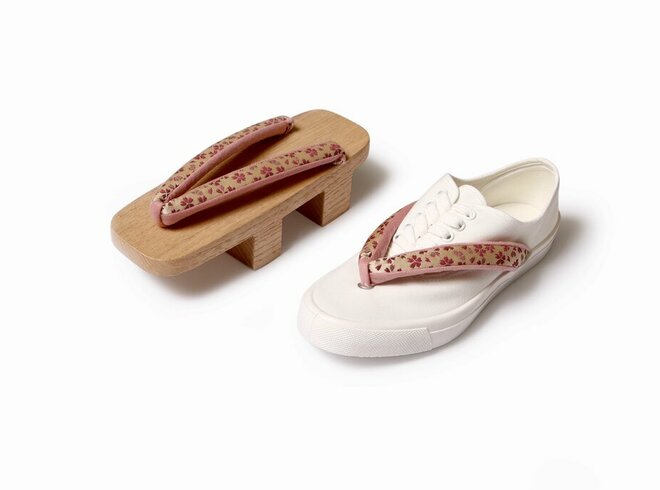 Ein weißer Sneaker neben traditionellen japanischen Geta-Holzsandalen auf weißem Hintergrund, ein Konzept, das moderne und traditionelle Schuhmode verbindet
