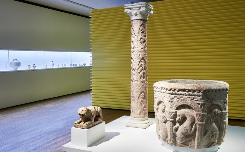 Raumaufnahme; drei antike Objekte aus Stein; eine Säule, ein Becken und die Statue einer Großkatze