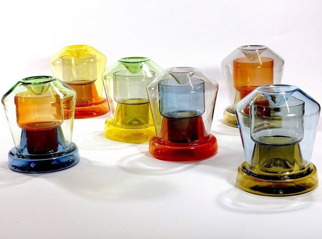 Eine Sammlung von sechs farbenfrohen, durchsichtigen Glaskaraffen auf einem weißen Hintergrund