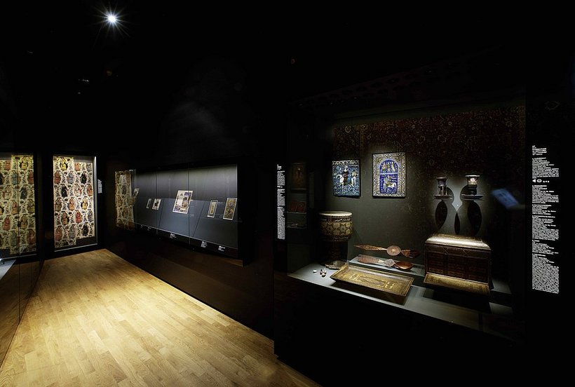 Ausstellungsansicht: abgedunkelter Raum mit einer großen Vitrine mit Objekten