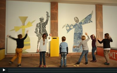 Screenshot: Sechs Kinder schauen auf Projektionen an der Wand und bewegen sich dazu