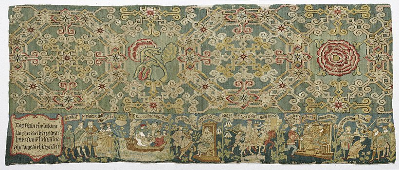 reichverzierte gewebte Textile mit geometrischem Muster und figürlichen Motiven, hauptsächlich grün und gold