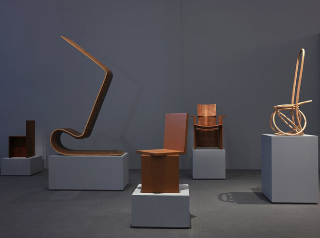Eine Ausstellung von verschiedenen, abstrakten, braunen Stühlen auf einem grauen Potest