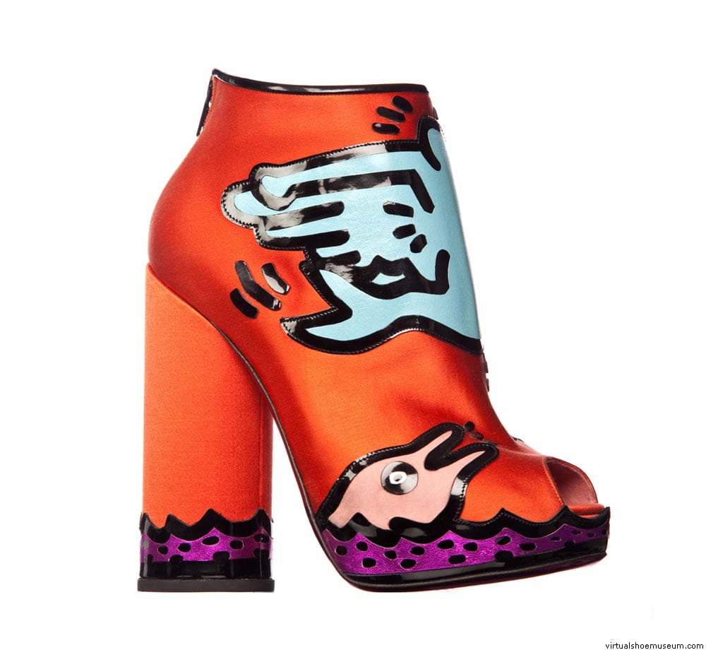 Ein auffälliger, orangener Stiefelette im Pop-Art-Stil, bemalt mit einem blauen Flügel